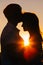 Romantic silhouette couple standing and kissing on background summer meadow sunset