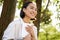 Romantic smiling girl reading book in park or foret, sitting under tree shade on sunny day, relaxing on fresh air