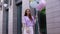 Romantic smiling red-haired girl standing with large fountain of colorful balloons outside.