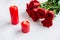 Romantic still life, there are two red burning candles and a bouquet of roses on the table