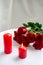 Romantic still life, there are two red burning candles and a bouquet of roses on the table