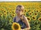 Romantic summer portrait of a beautiful teenage girl in a blue sundress standing in a sunflower field at sunset. The background is