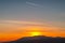 Romantic sunset sky with airplane trail and mountains on the background