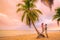 Romantic sunset stroll young couple in love embracing on palm trees at pink dusk clouds sky. Romance on summer travel