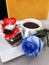 A romantic table, a branch of a blue rose, a cup of coffee and a delicious dessert in front of a yellow background