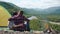 Romantic tourist couple hugging at camp site with bonfire on rocky top of hill in green mountains