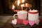 Romantic Valentine`s Day, Warm Fireplace Scene with Red and Pink Cocoa Mugs and Wood Hearts Garland in Cozy Living room with space