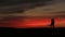 Romantic walk of the adorable couple tenderly kissing over the red and gray sky during the sunset. Full-length view of