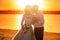 Romantic wedding couple at sunset on the shore with a guitar. The bride and groom near the shore on a sunset beach in summer