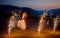 Romantic wedding shot of the kissing newlyweds. The groom is lifting up the bride on the mountains decorated with