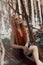 Romantic woman with red hair lying in the grass in the woods. A girl in a light black dress sleeps and dreams in a magical forest.