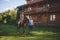 Romantic young couple in love, a walk on a horse on nature background and wooden country-style hotel. Young woman