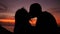 Romantic young couple silhouette embrace and kiss at amazing sunset. HD Slow Motion. Phangan, Thailand.