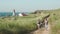 Romantic young couple walks holging hands together, talking and laughing on sand trail near lighthouse at seashore cliff