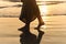 Romantic young girl walks on the beach barefoot in the water. Woman stroll barefoot in the sea at sunset.