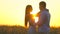 Romantic young happy couple silhouette in golden wheat field at sunset. Woman and man hugging and kissing against