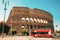 Rome, Italy. Colosseum. Red Hop On Hop Off Touristic Bus For Sightseeing In Street Near Flavian Amphitheatre. Famous