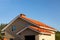 The roof of a brick house or cottage with slopes, tides, chimney against the blue sky. Roof made of red metal tiles for design on