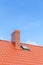 Roof with ceramic tile chimney against blue sky.