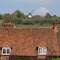 Roof of characterful cottage in the village of Turville in the Chilterns, with Cobstone Mill at the top of the hill behind.