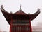 The roof of a chinese temple with a misty background