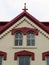 Roof gable with arched windows, painted cream brick, and red trim