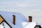 Roof of the house with brick chimneys covered with snow in winter