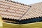 Roof house with tiled roof on blue sky. detail of the tiles and corner mounting on a roof, horizontal. roof protection from snow