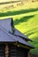 The roof is made of gray embossed metal sheets. Wooden house in the summer fiel