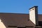 Roof of a new home. Ceramic chimney, metal roof tiles, gutters, roof window. Single family house