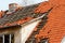 The roof of the old house with a damaged coating of red ceramic tiles