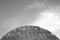 Roof of old metal hangar against cloudy sky in black and white