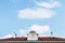 Roof of an old train station with a beautiful clock and a summer sky