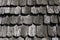 Roof shingles as a traditional rural roof covering. Tiled acute angled cross slab roofing piece material close-up