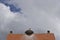 Roof with storks nest and a cloud-covered sky.