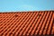 Roof tile, or painted concrete, orange with ventilation and a top row on the ridge. blue sky, side view