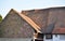 The roof of a very old house is covered with tiles of different types and moss grows on it. The concept of diversity and
