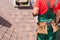 Roofer builder worker with bag of tools installing roofing shingles.