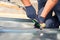 Roofer builder worker finishing folding a metal sheet using rubber mallet