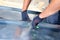 Roofer builder worker finishing folding a metal sheet using special pliers with a large flat grip.