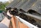 Roofer Cleaning Rain Gutter from Leaves in Spring. Roof Gutter Cleaning Tips. Clean Your Gutters Before They Clean Out Your Wallet