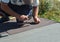 Roofer with hammer and nails laying asphalt shingles tiles on house roof. Roofing Construction