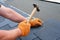 Roofer hands installing bitumen roof shingles using hammer in nails