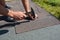 Roofer installing Asphalt Shingles on house construction roof corner with hammer and nails. Roofing construction with Asphalt