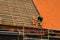 Roofer in protective workwear installing new clay tiles, new clay tiles layer covering