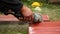 Roofer using an angle grinder machine to cut a roof tile of red color. Stock footage. Close up of male worker hands