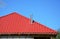Roofing Construction. New red metal tiled roof with steel chimney house roofing construction exterior without rain gutter system.