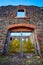 Roofless abandoned building with red stone brick and multicolored stone building with missing window above double door