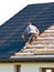 Rooftop worker installing new metal tiles on a house