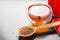 Rooibos in spoon closeup, two tea cups and tea tin box on table